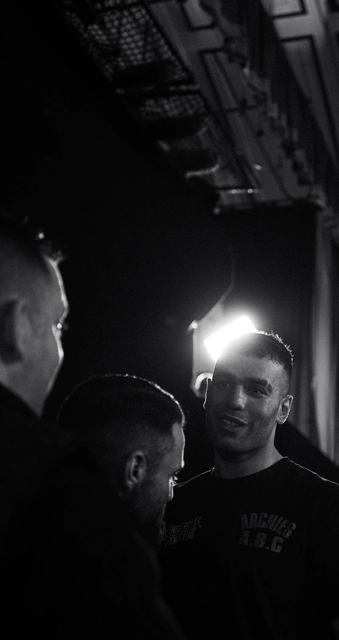A boxer talking with his team backstage, in black and white