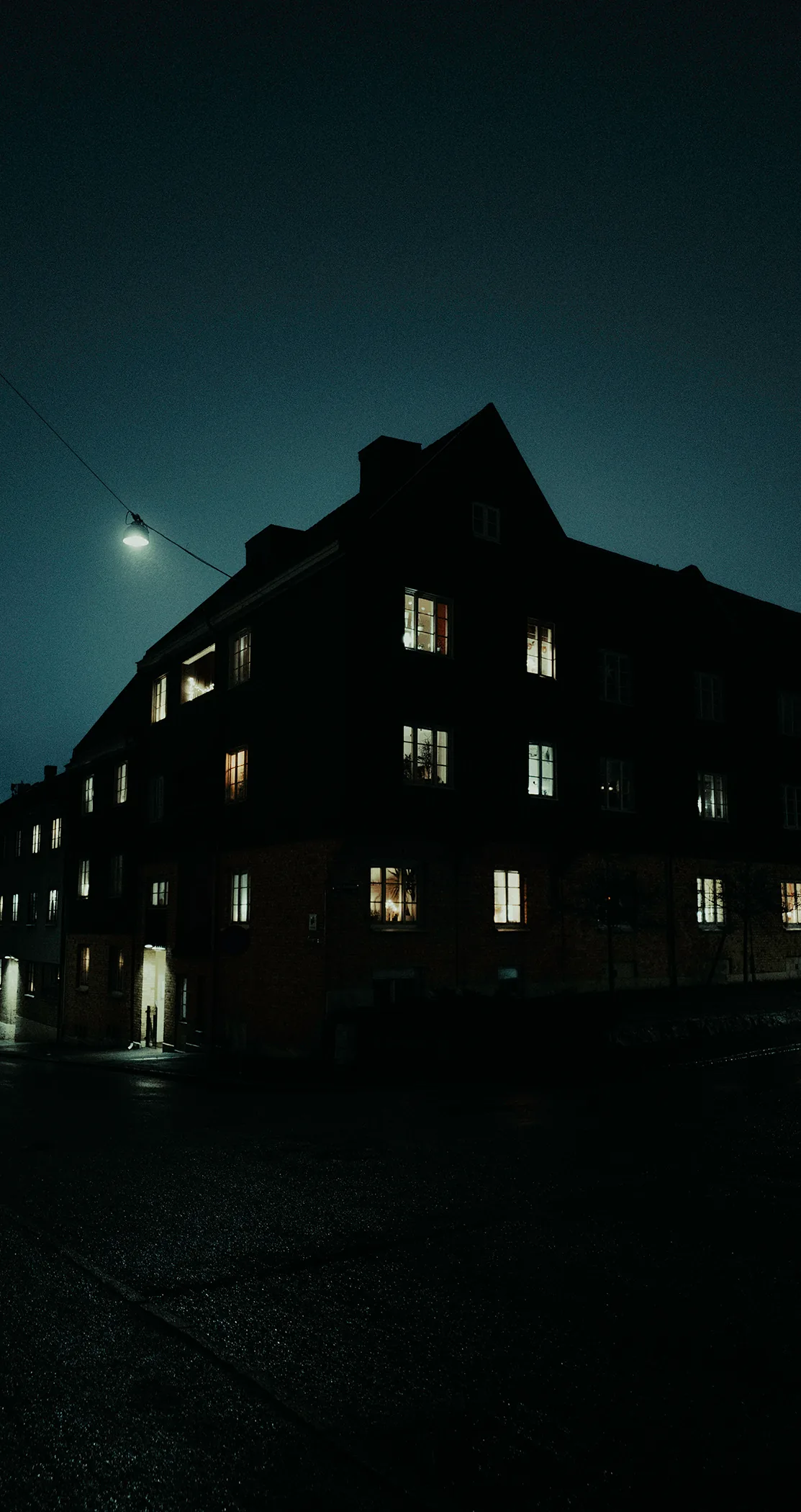 An apartment block in silhouette at night with a few windows lit