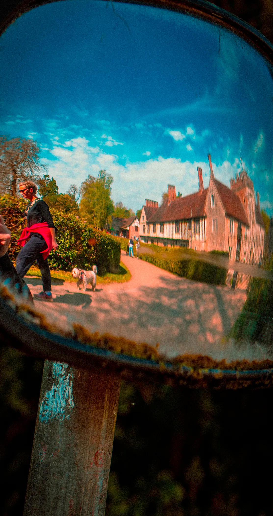A manor house and a dog walker reflected in a convex road mirror, Sevenoaks