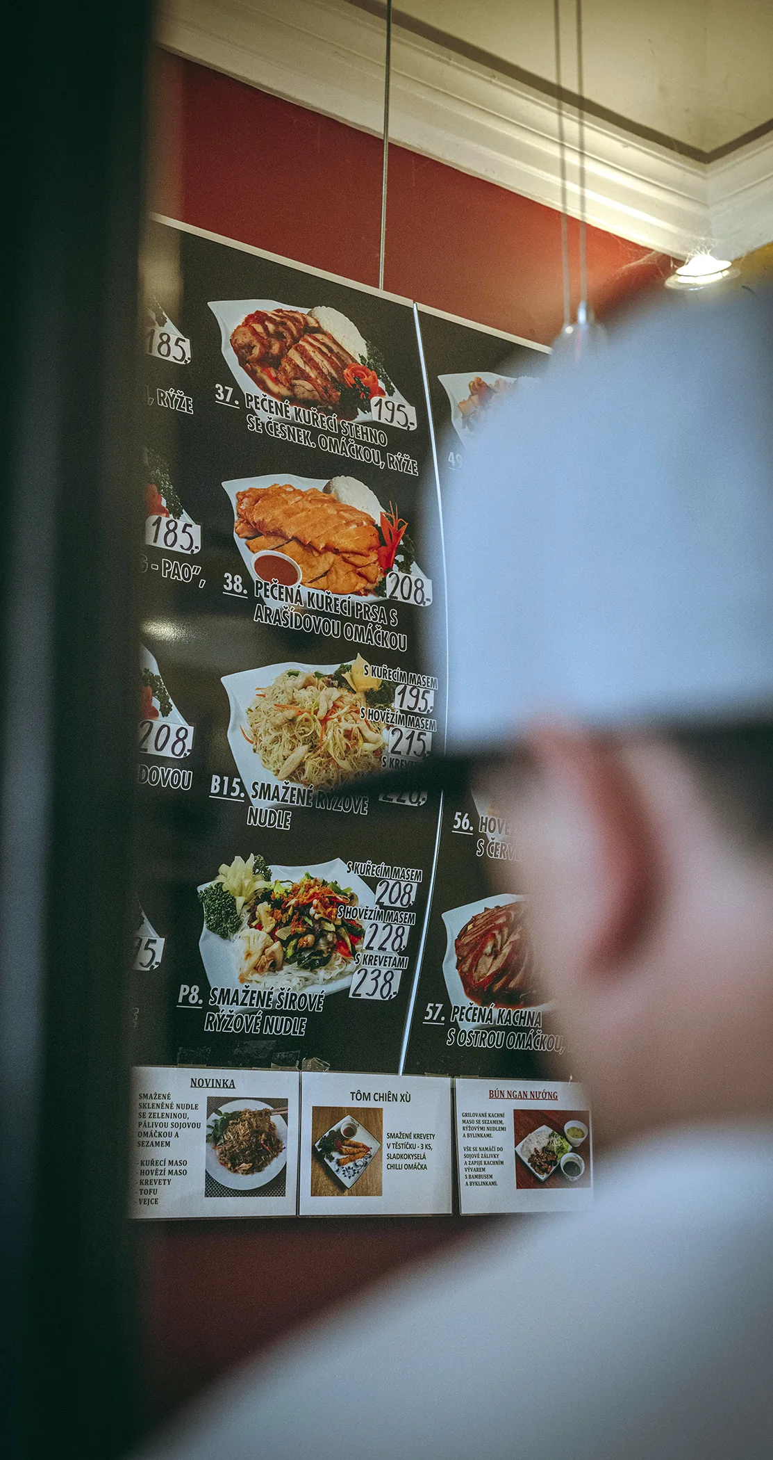 A chef in a white cap facing an illuminated menu board